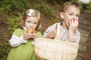 adorables enfants mangeant des pommes rouges à l'extérieur photo