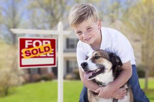 garçon et son chien devant le signe vendu, maison photo