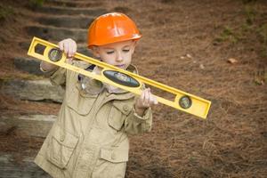 adorable enfant garçon avec niveau jouant bricoleur à l'extérieur photo