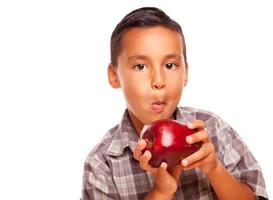 adorable garçon hispanique mangeant une grosse pomme rouge photo