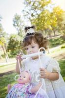 adorable jeune fille jouant avec une poupée et un chariot photo