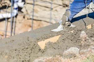 Ouvrier en construction de piscine travaillant avec un flotteur en bois sur du béton humide photo