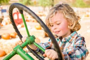 petit garçon s'amusant dans un tracteur dans un ranch rustique au champ de citrouilles. photo
