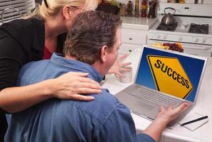 couple dans la cuisine à l'aide d'un ordinateur portable - signe de réussite photo