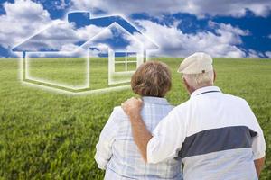 Senior couple standing in grass field looking at ghosted house photo