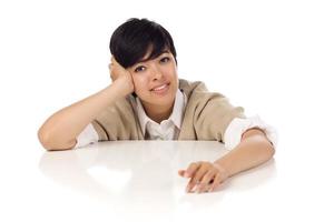 jeune femme adulte de race mixte souriante assise à une table blanche photo