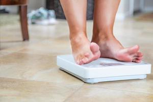 femme debout sur une balance à la maison regardant à contrecœur son poids photo