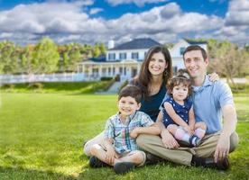 heureuse jeune famille avec enfants à l'extérieur devant une belle maison personnalisée. photo