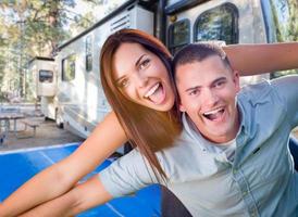 jeune couple militaire adulte devant leur magnifique camping-car au camping. photo