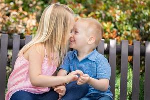 jeune soeur et frère s'amusant sur le banc du parc photo