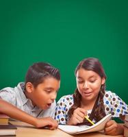 tableau de craie vierge derrière un garçon et une fille hispaniques s'amusant à étudier ensemble photo