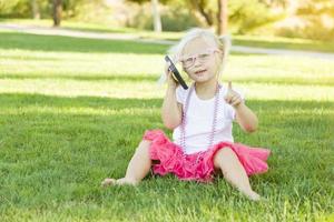 petite fille dans l'herbe parlant au téléphone portable photo