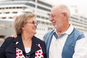 couple de personnes âgées à terre devant un bateau de croisière photo