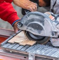 Travailleur utilisant une scie à carreaux humide pour couper des carreaux muraux sur un chantier de construction photo