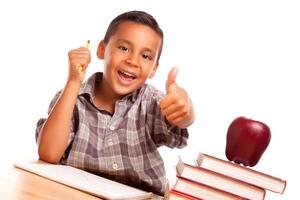 adorable garçon hispanique avec livres, pomme, crayon et papier photo