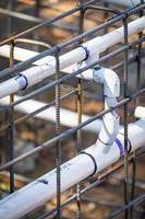 tuyaux de plomberie en pvc nouvellement installés et configuration des barres d'armature en acier sur le chantier de construction photo