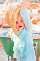 adorable petite fille avec chapeau de cow-boy dans un cadre rustique au champ de citrouilles. photo