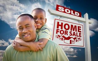 père afro-américain avec fils devant la maison vendue à vendre signe immobilier photo