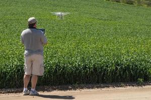 pilote aux commandes d'un drone d'aéronef sans pilote recueillant des données sur un champ de terres agricoles photo