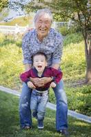 grand-père chinois s'amusant avec son petit-fils métis à l'extérieur photo