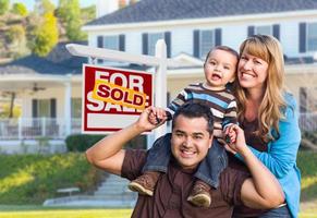 jeune famille devant l'enseigne et la maison de l'immobilier vendu photo