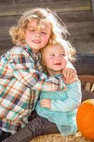 adorable petit garçon joue avec sa petite sœur dans un ranch rustique au champ de citrouilles. photo