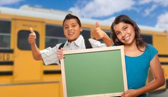 jeunes étudiants hispaniques avec tableau blanc près de l'autobus scolaire photo