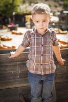petit garçon debout contre le vieux chariot en bois au champ de citrouilles photo