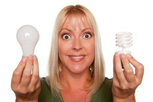 femme tient des ampoules à économie d'énergie et régulières photo