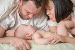 Mixed Race Chinese and Caucasian baby boy allongé dans son lit avec ses parents photo