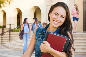 Étudiante de jeune fille de race mixte avec des livres scolaires sur le campus photo