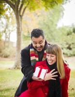 couple mixte partageant un cadeau de noël ou de saint valentin à l'extérieur photo