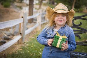 jeune fille portant des vêtements de vacances tenant un cadeau de noël à l'extérieur photo