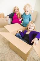 jeune famille dans une pièce vide jouant avec des cartons de déménagement photo