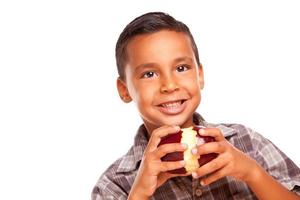 adorable garçon hispanique mangeant une grosse pomme rouge photo