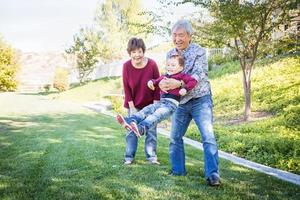 heureux grands-parents chinois s'amusant avec leur petit-fils métis à l'extérieur photo