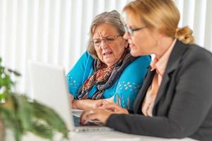 femme aidant une dame adulte âgée sur un ordinateur portable photo