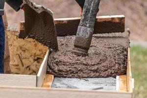 travailleur de la construction nivelant du ciment humide dans une charpente en bois photo