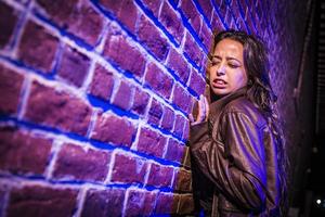 Jolie jeune femme effrayée contre le mur de briques la nuit photo