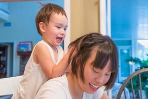 heureux métis chinois et caucasien garçon s'amusant avec une mère chinoise à l'intérieur de la maison photo