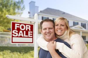 couple devant une nouvelle maison et une enseigne immobilière photo