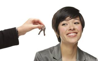 jeune femme métisse recevant des clés sur blanc photo