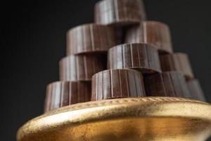 pile de chocolats fins sur plat pilier doré avec fond sombre photo