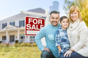 portrait de famille métisse devant la maison et à vendre enseigne immobilière photo