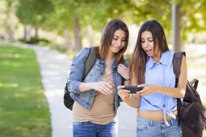 jeune adulte métisse soeurs jumelles partageant l'expérience du téléphone portable photo