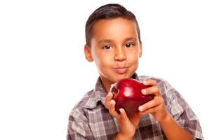 adorable garçon hispanique mangeant une grosse pomme rouge photo