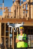 une femme pilote vole un drone quadricoptère inspectant un chantier de construction photo