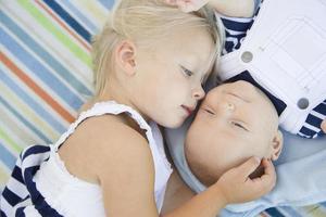 petite soeur allongée à côté de son petit frère sur une couverture photo