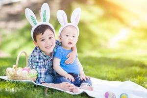 Mixed race chinois et garçons de race blanche à l'extérieur dans le parc jouant avec des oeufs de pâques photo