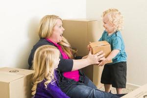 jeune famille dans une pièce vide jouant avec des cartons de déménagement photo